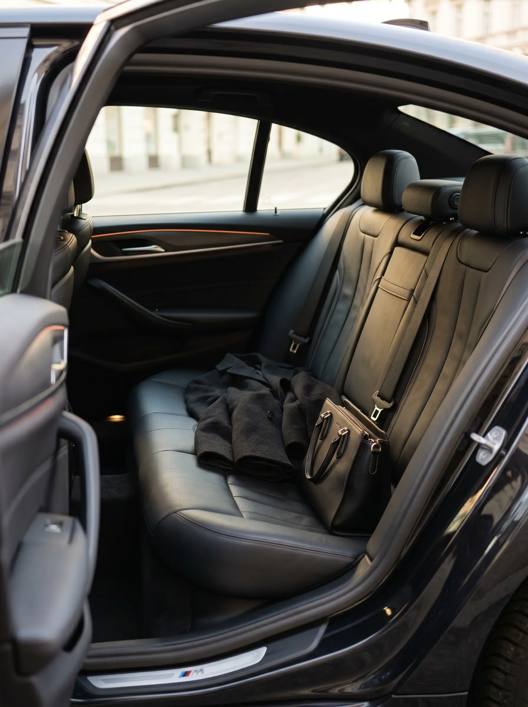 BMW 5 Series M rear interior with black leather, coat and bag