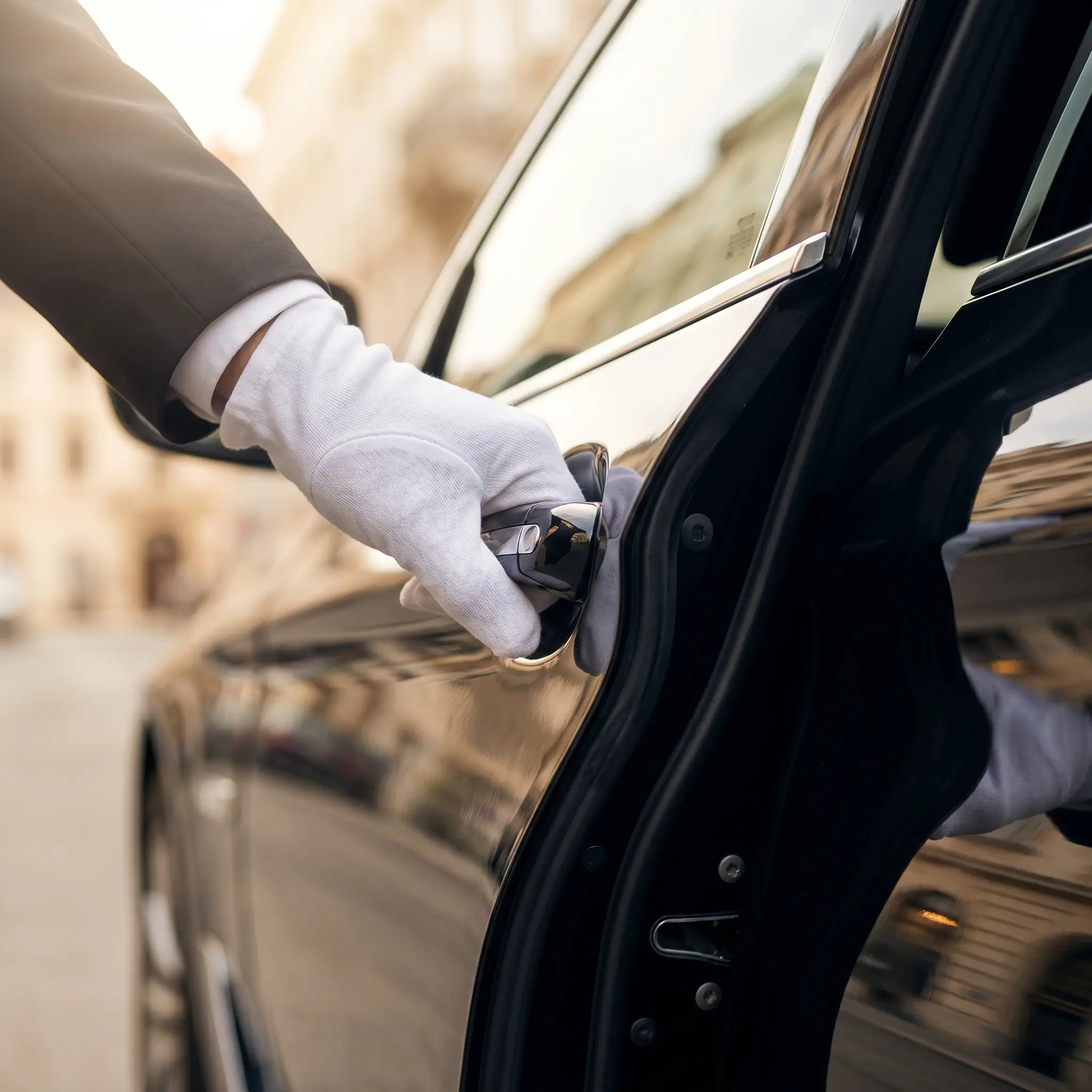 Chauffeur mit weißem Handschuh öffnet Fahrzeugtür